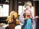 A woman in a blue and red kimono standing in a room.