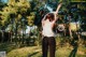 A woman in a white tank top and black leggings standing in a park.