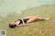 A woman in a black bathing suit laying in the water.