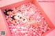 A woman laying in a pink bathtub filled with pink balloons.