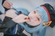 A woman with blue hair wearing a black jacket and a red headband.