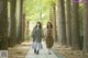 Two women walking down a path in a park holding hands.