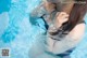 A woman in a swimming pool with her hands on her neck.