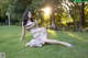 A woman in a gold dress sitting on the grass.