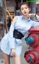 A woman leaning against a red fire hydrant on a city street.