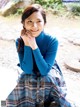 A woman in a blue sweater and plaid skirt posing for a picture.