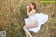 A woman in a white dress sitting in a field of tall grass.