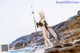 A woman in a bikini standing on a rock by the ocean.