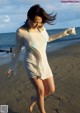 A woman in a white dress is running on the beach.