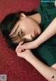 A woman laying on a red carpet with her head resting on her hands.