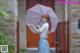 A woman holding an umbrella standing in front of a building.